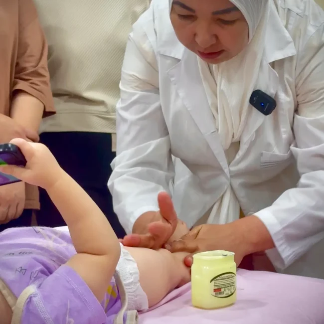 Hamshira go'dakning oyoqlarini massaj darsida uqalayapti.